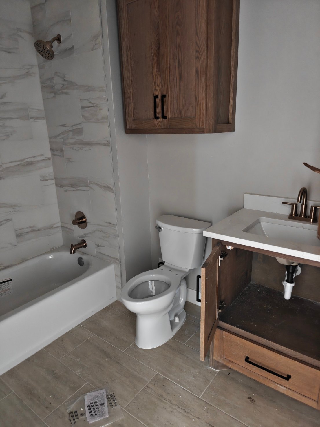 Finished bathroom trim-out with toilet, tub, and vanity faucet installed
