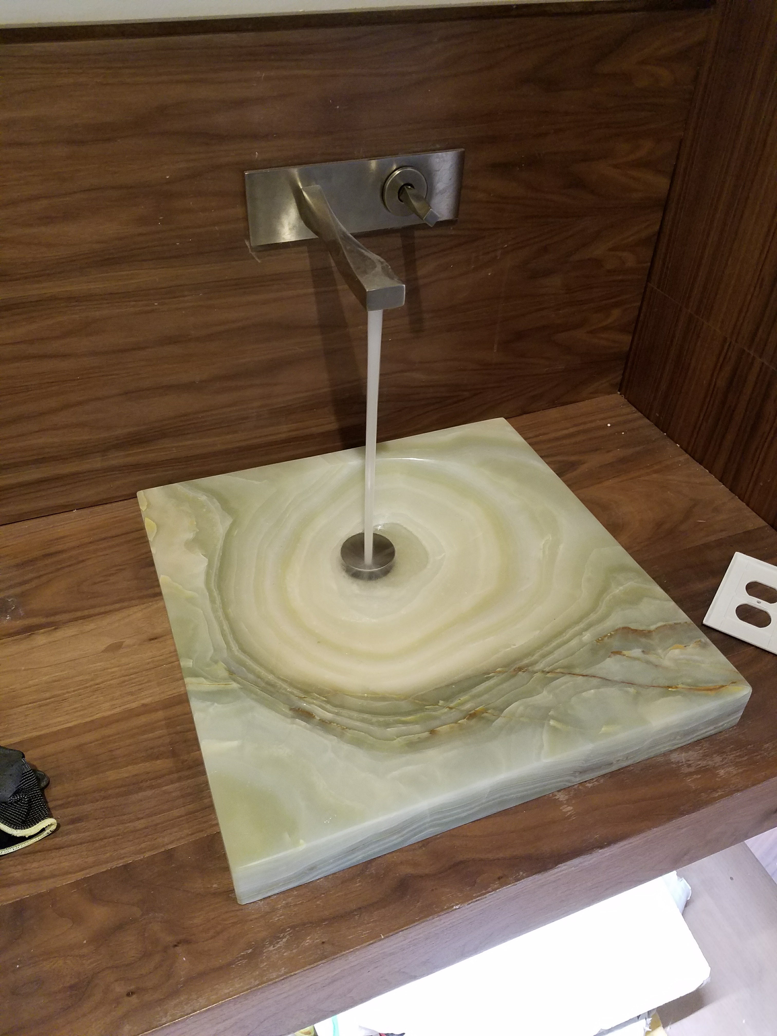 Wall-mounted faucet installed over a stone vessel sink
