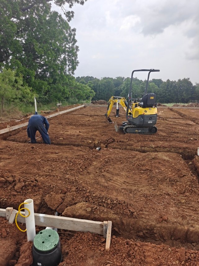 Underground plumbing rough-in on a new construction lot with a mini excavator