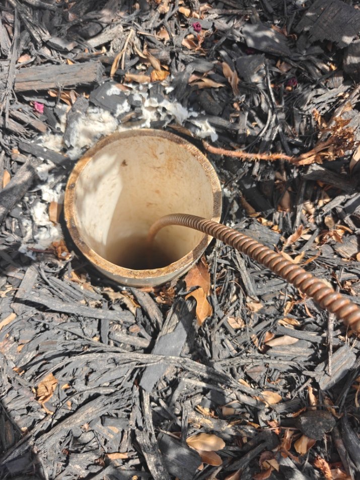 Drain cable fed into an outdoor sewer cleanout during a drain cleaning job